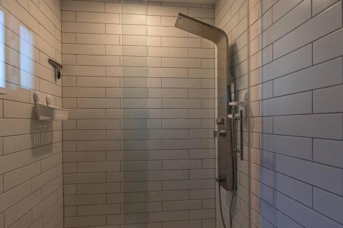 W łazience z białymi ścianami wyłożonymi kafelkami znajduje się prysznic. w obiekcie NEW! Chic & Cozy Lantana near the Beach & Flagler w mieście New Smyrna Beach