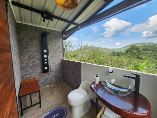 uma casa de banho com um WC e um lavatório de vidro em El eden hotel Boutique em Sasaima