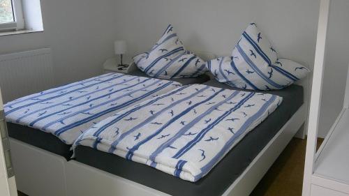 a bed with blue and white sheets and pillows at Unseburger Brauhaus GmbH Ferienwohnung 2 in Unseburg
