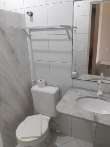 a white bathroom with a toilet and a sink at Ponta Negra Palace in Natal