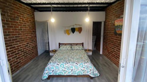 ein Schlafzimmer mit einem Bett in einer Ziegelwand in der Unterkunft Cabañas “Pacha Mama” in Roldanillo
