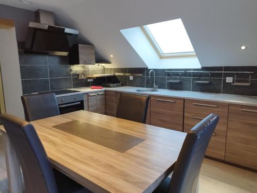 une cuisine avec une table en bois et une lucarne dans l'établissement Le chalet du Sersas, à Saint-Clément sur Durance