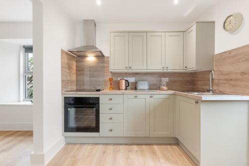 a kitchen with white cabinets and an oven at Delightful Family Getaway Cornwall in Mawnan Smith