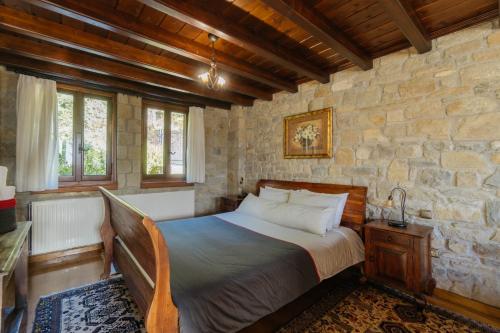 a bedroom with a bed and a stone wall at Τα Πέτρινα της Ελάτης - Petrina Elatis in Elati Trikalon