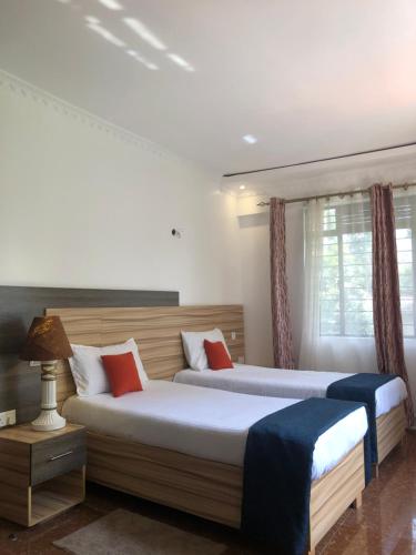 a bedroom with two beds and a window at Savwa Resort and Gardens in Kakamega