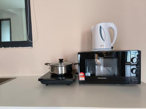 a microwave oven with a pot on top of it at New 2BR or 3BR Cozy Urban Suite Homestay at Georgetown8-10pax by URBAN STAYCATIONS LOD in Jelutong