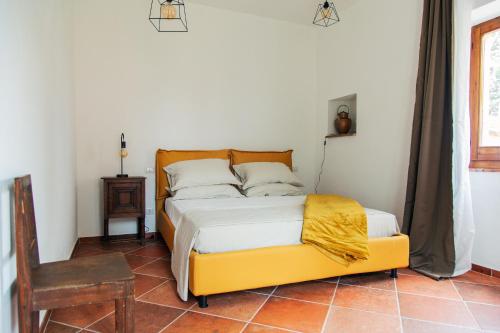 a bedroom with a bed with a yellow frame and a chair at Villa Orta - Agriturismo con cucina Vegan, Plant-based Farmhouse in Riotorto