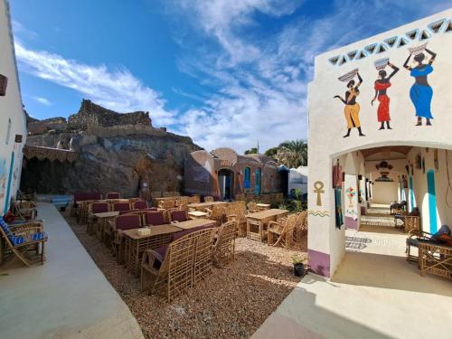 ein Gebäude mit einer Gruppe von Tischen und Stühlen in der Unterkunft Miskaa Nubian House in Naj‘ Tinjār