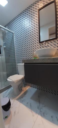 a bathroom with a toilet and a sink and a mirror at Apartamento Mania Terceiro Andar in Vitória