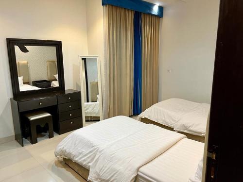 Habitación de hotel con 2 camas y espejo en Al-Aniqa Furnished Apartments en Riad