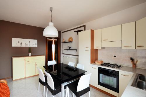 cocina con mesa negra y armarios blancos en Magica Immobiliare - Villa Mimosa 11, en Lido di Jesolo