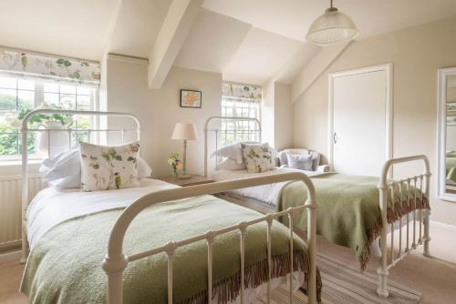 a bedroom with two beds and two windows at Huckleberry Cottage in Hope Cove