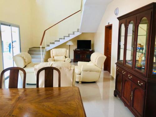 a living room with white furniture and a staircase at Hotel Toolbi in Niaga