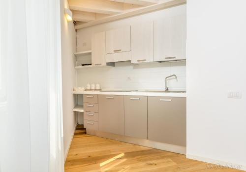 a kitchen with white cabinets and a wooden floor at Palazzo Chimelli in Pergine Valsugana
