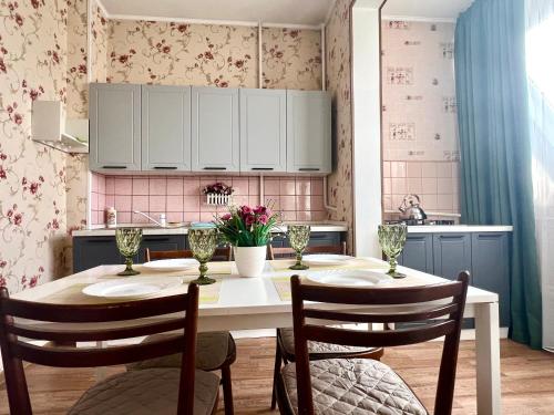 a kitchen with a table with chairs and flowers on the wall at Cozy three-room apartment with Mountain view in Almaty
