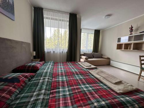 een slaapkamer met een groot bed en een geruite deken bij Borovets Gardens Funky Fresh Studio by Joro in Borovets