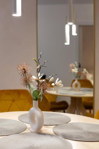 a white vase with flowers in it sitting on a table at Apartamenty Cicha - bezpłatny parking in Krynica Zdrój