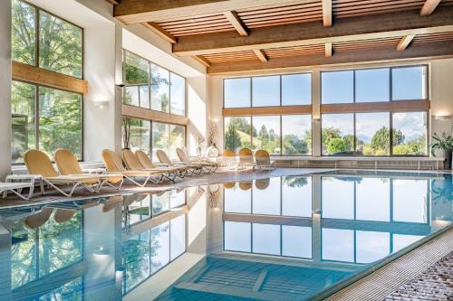 an indoor swimming pool with chairs and windows at Inntaler Hof in Seefeld in Tirol