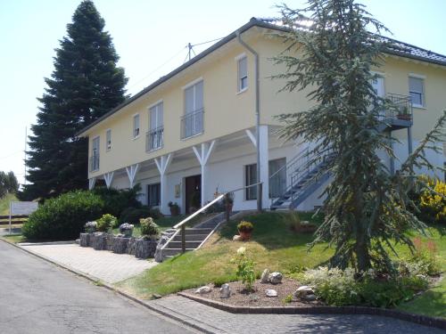 un edificio blanco con un árbol delante en Carpe Diem en Kelberg