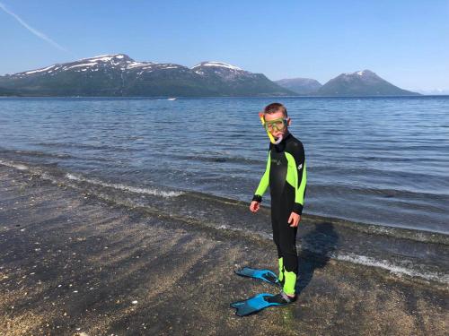 a man in a wetsuit standing on the beach at Large house with spectacular view in Tromsø