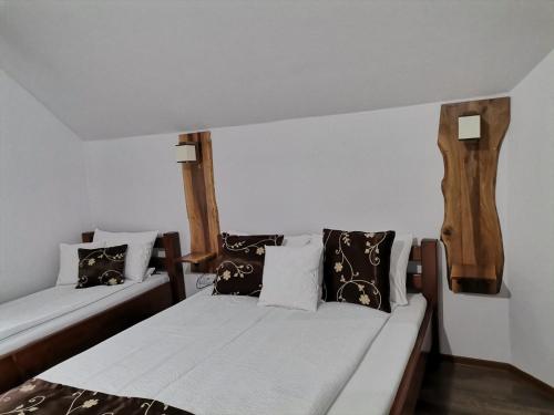 2 camas en una habitación con almohadas blancas y marrones en Dió vendégház en Praid