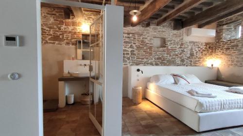 um quarto com uma cama branca e uma parede de tijolos em Borgo Calbianco - Private House with Pool & AirCo em Cereto