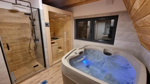 uma grande banheira azul na casa de banho com chuveiro em Gorska bajka - Borovica, planinska kuća za odmor i wellness em Stara Sušica