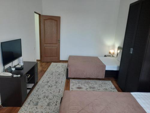 a hotel room with two beds and a television at Апарт отель Welcome in Taldykorgan