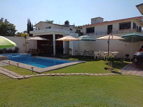 Casa con patio con piscina y sombrillas en Casa vacacional BREAKEVEN en Oaxtepec