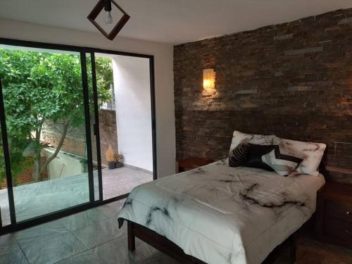 1 dormitorio con cama y pared de ladrillo en Casa vacacional BREAKEVEN en Oaxtepec