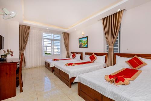 Habitación de hotel con 3 camas y escritorio. en ANH TUẤN HOTEL, en Vung Tau