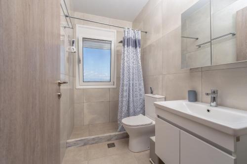 a bathroom with a toilet and a sink and a window at Piperitsa house for nomads or families in the countryside in Messini