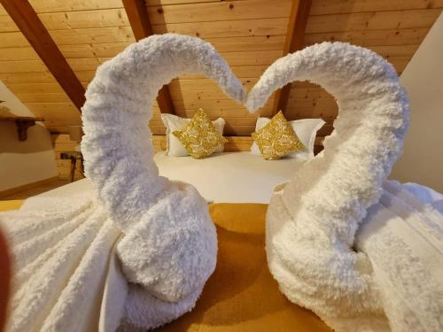Una cama con dos corazones hechos de toallas en Casuta Armonia en Moisei