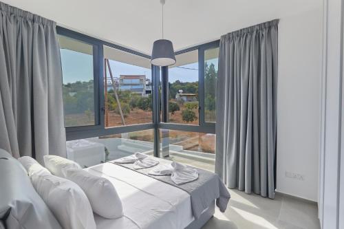 a white bedroom with a bed and a large window at Elite Pearl Villas in Protaras
