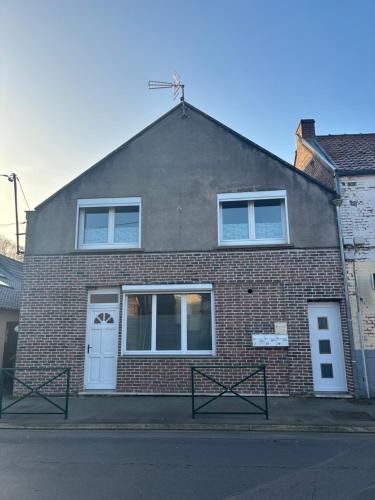 een stenen huis met een witte deur en ramen bij Appartement tout confort 60 m² in Haveluy