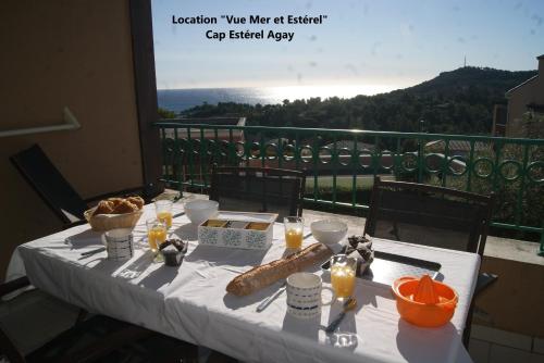 uma mesa com uma toalha de mesa branca e comida numa varanda em "Location Vue MER et ESTEREL", Cap Estérel Agay-Saint Raphaël, T2, piscines, parking, wifi em Saint-Raphaël