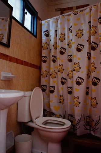 a bathroom with a toilet and a shower curtain with bears at Estrelitzia Hospedaje in Reyes