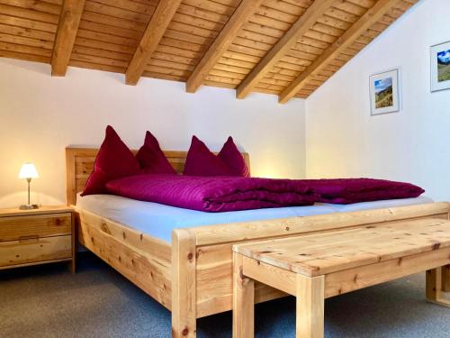 Un dormitorio con una gran cama de madera con almohadas rojas en Chasa Sot-Chaunt 301 en Samnaun