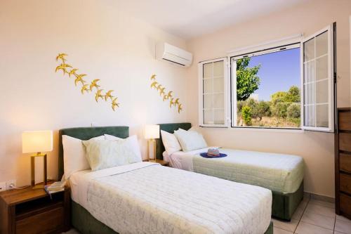 a bedroom with two beds and a window at Olive Garden Residence in Platanes