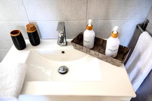 a bathroom sink with three bottles of soap on it at Seaside Serenade 1, suite in Ermoupoli