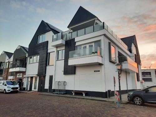 a large white building with a car parked in a parking lot at Bij de Haven op Urk in Urk