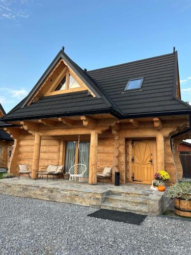 a log cabin with a black roof and a porch at Uroczy drewniany domek - Domki pod Brzegiem in Zakopane