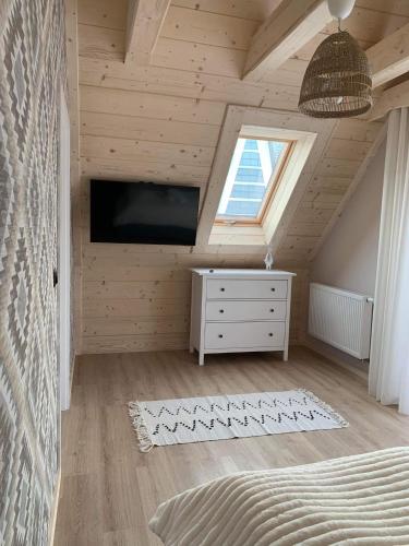 a bedroom with a bed and a tv and a window at Uroczy drewniany domek - Domki pod Brzegiem in Zakopane