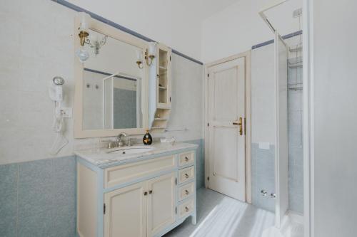 uma casa de banho com um lavatório, um espelho e um chuveiro em La Tana dei Tassi em Ascoli Piceno