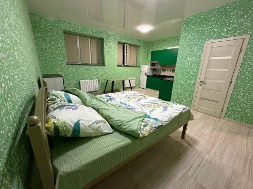 a bedroom with green walls with a bed and a kitchen at Днестровский in Kharkiv