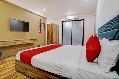 a bedroom with a bed with red pillows and a tv at OYO Hotel Green Signature in Surat