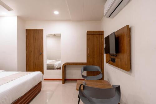 Schlafzimmer mit einem Bett, einem Schreibtisch und einem TV in der Unterkunft hotel silver tree in Rajkot