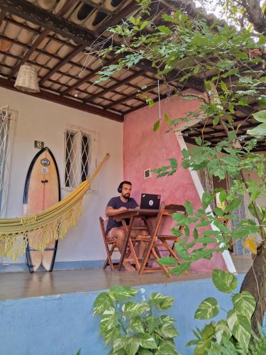 a man sitting at a table with a laptop at Stay Cool Pipa in Pipa