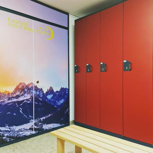 a locker room with red lockers and a wooden bench at Hotel Mondschein in Sesto