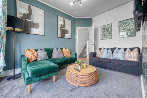a living room with a green couch and a table at Stunning Design 3-Bedroom Townhouse Retreat in Southsea, Sleeps 8, Chic and Spacious with Free Parking Permit, SPRING SPECIAL OFFER AVAILABLE! - by Blue Puffin Stays in Portsmouth